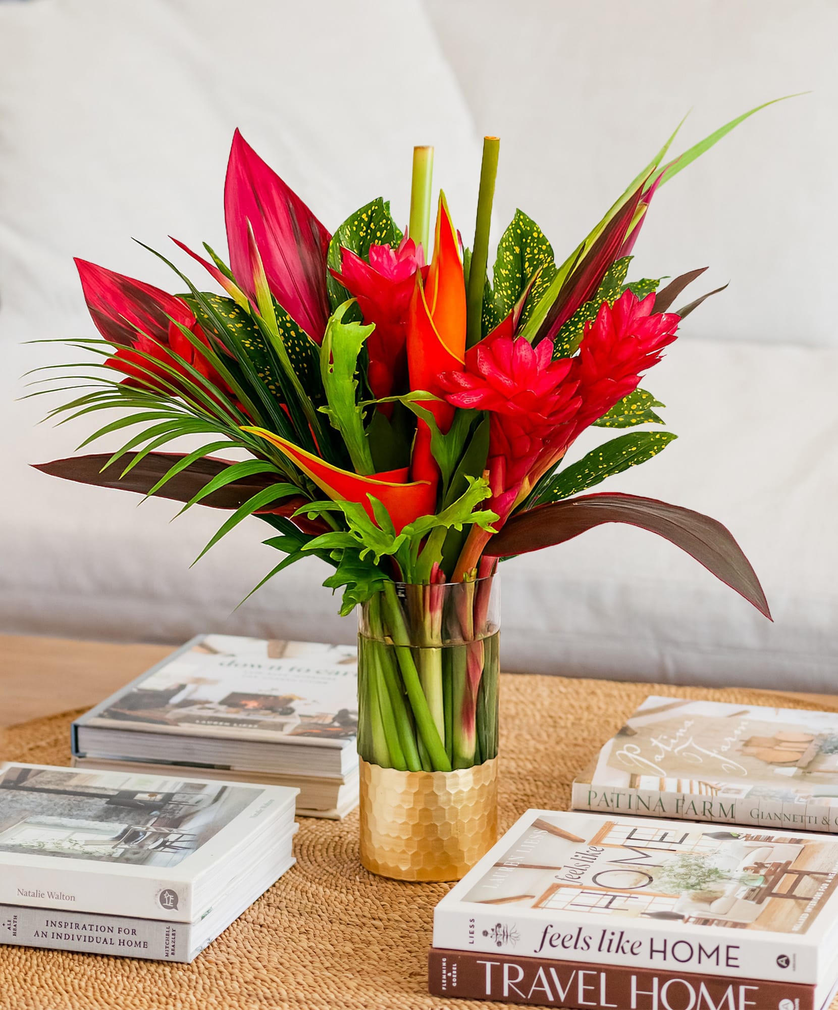 Vibrant tropical flower arrangement featuring red and green foliage in a stylish vase.