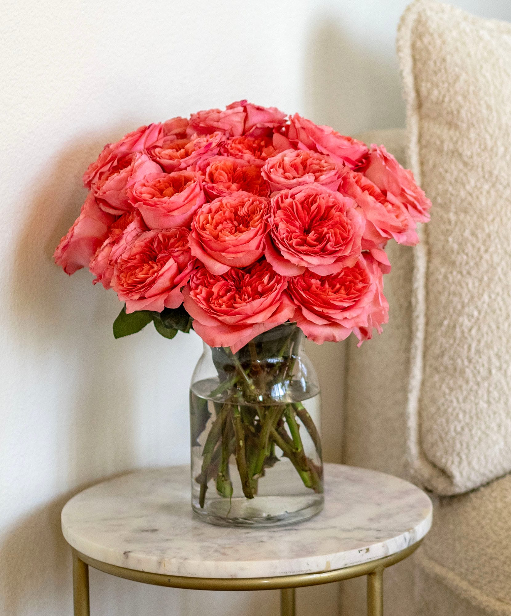 A stunning arrangement of vibrant pink roses in a clear glass vase on a stylish table.